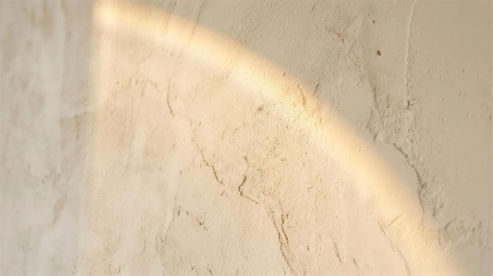 Warm ivory plaster wall with a soft arc of morning light
